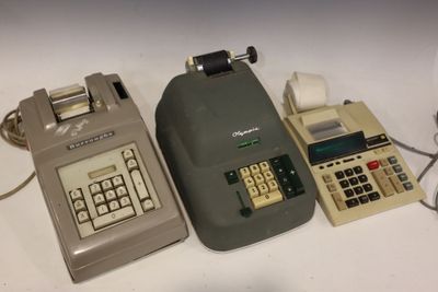 trois vieilles calculatrices posées les unes à côté des autres sur une table