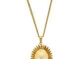 a gold necklace with a sunburst pendant on a chain
