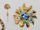 a gold brooch with a blue stone and a gold chain