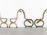 three metal giraffes are lined up in a row against a white wall