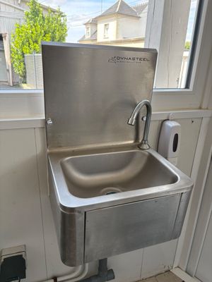 a stainless steel sink in the corner of a bathroom