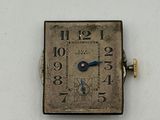 a small square silver clock with blue hands on a white surface