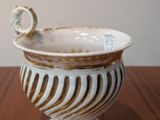 a white and gold vase sitting on a wooden table