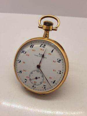 une petite montre de poche en or posée sur une surface blanche
