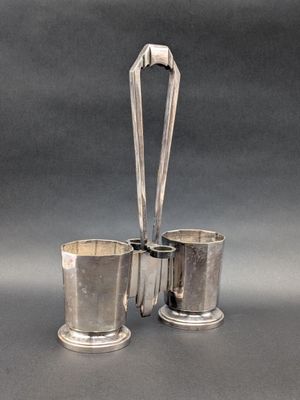 deux tasses et cuillères plaquées argent posées sur un support gris