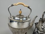 a silver tea pot and a silver teapot on a stand