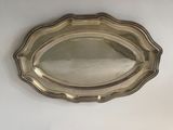 an oval silver tray with a decorative design on the rim