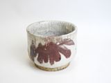 a close up of a small bowl with a leaf design on it