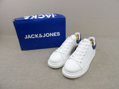 des baskets blanches à semelles bleues et une boîte bleue posée sur une table