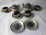 five pieces of silver and gold tea set on a white table