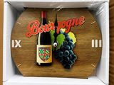 une horloge en bois sur laquelle sont représentés une bouteille de vin et des raisins