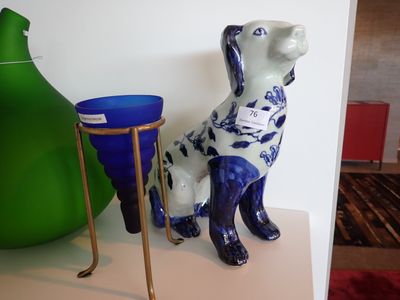 une statue de chien bleue et blanche posée sur une étagère à côté d'un vase vert