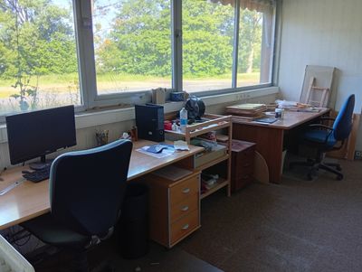 un bureau avec deux ordinateurs et une chaise devant une fenêtre