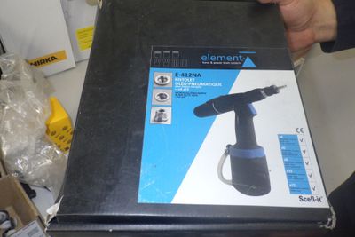 Quelqu'un tient une boîte dans laquelle se trouve une perceuse électrique noire.