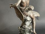statue of a woman sitting on a rock with a bird in her hand