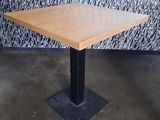 a wooden table with a metal base in front of a wall