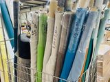 many rolls of fabric in a wire basket on the floor