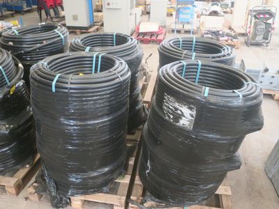 de nombreux tuyaux noirs empilés sur des palettes dans un entrepôt