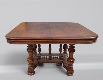 une vieille table en bois avec un plateau sculpté et des pieds tournés