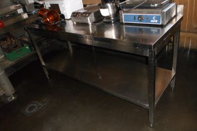 une grande table en acier inoxydable au milieu d'une cuisine