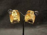 pair of gold plated earrings on a black stand against a black background
