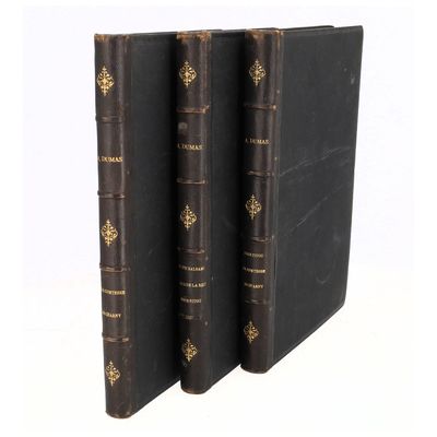 trois livres noirs à la reliure dorée, posés les uns à côté des autres