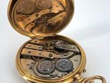 a gold pocket watch with gears inside of it on a white surface