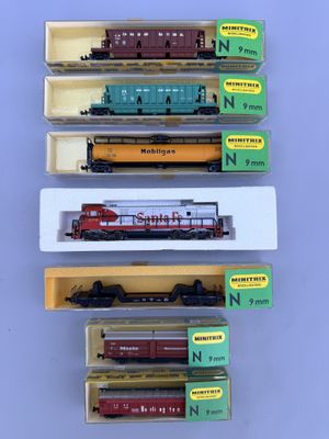 four different model trains are in boxes on a table