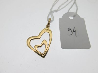 un gros plan sur un pendentif en forme de cœur en or avec une étiquette de prix