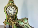 a green and gold clock sitting on a wooden table