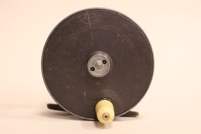 a black reel with a yellow handle on a white surface