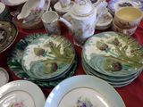 many plates and cups sitting on a table with a red table cloth