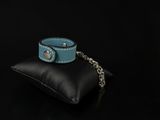 blue leather bracelet with a chain on a black pillow