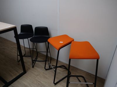 trois tabourets noirs et orange placés les uns à côté des autres sur un parquet