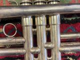 a silver trumpet sitting on a rug on the floor