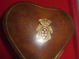 une boîte marron en forme de cœur, ornée d'un emblème doré