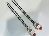 deux colliers noirs et blancs ornés de perles rouges sur un fond blanc