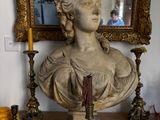 a bust of a woman sitting on a table next to a mirror