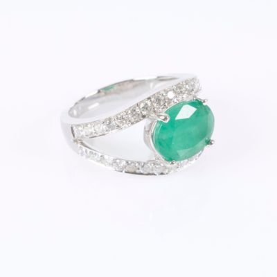 a close up of a ring with a green stone surrounded by diamonds