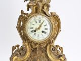 a gold clock that is sitting on a white surface