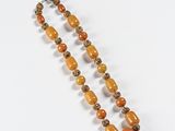 an orange beaded necklace on a white surface