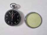 a pocket watch and a lip bale on a white surface