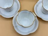 four cups and saucers are sitting on a table with a cake