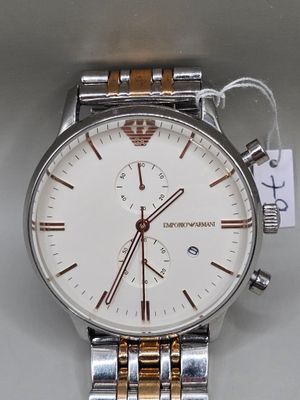 une photo d'une montre en argent et en or sur laquelle est accrochée une étiquette