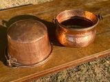 une casserole et une poêle en cuivre posées sur une table en bois