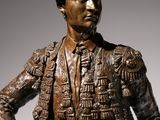 bronze statue of a man with a hat and jacket holding a cane