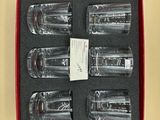 six empty shot glasses in a red box on a yellow surface