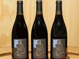 trois bouteilles de vin posées sur un tonneau en bois