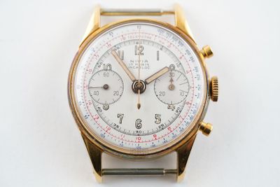 une montre en or avec un cadran blanc sur une surface blanche