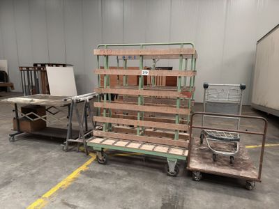 several pallets of wood sit in a warehouse with a cart in the foreground